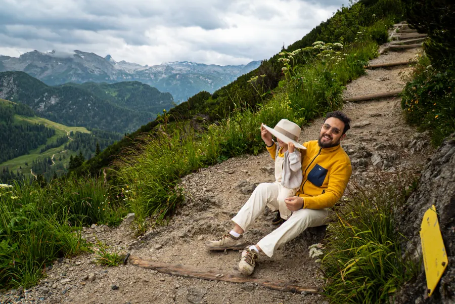 A parent and child resting on a green mountain path