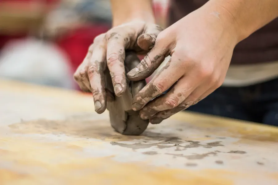 Hands shaping a clay pot on a pottery wheel