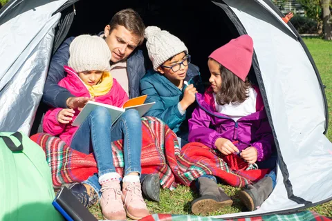 A family reading together inside a tent.