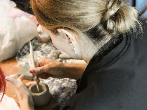 Group of adults engaged in a creative pottery workshop, crafting ceramic pieces.