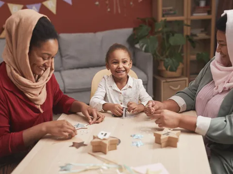 Three generations enjoying a creative crafting session together at home, full of smiles and family joy.