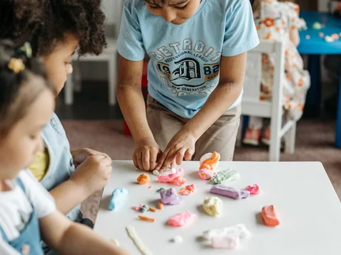 Young kids enjoy crafting with colorful clay in a playful, creative classroom setting.