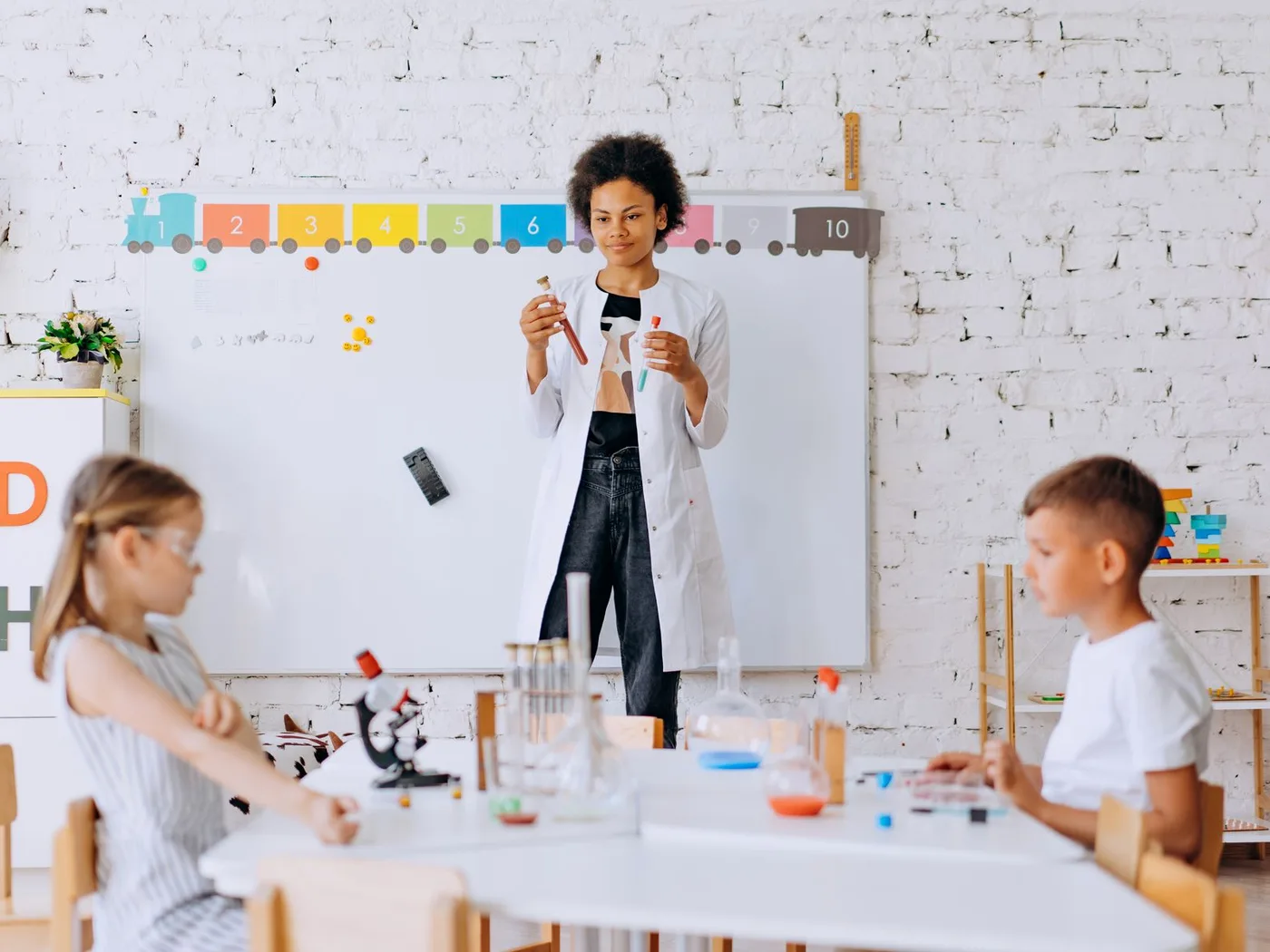 Children conduct a science experiment under teacher's guidance in a classroom setting.