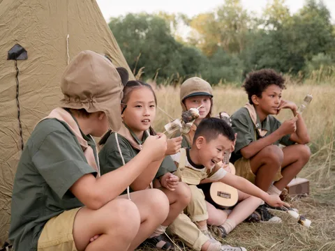 Children camping outdoors, roasting marshmallows near a tent. A fun and diverse camping experience.
