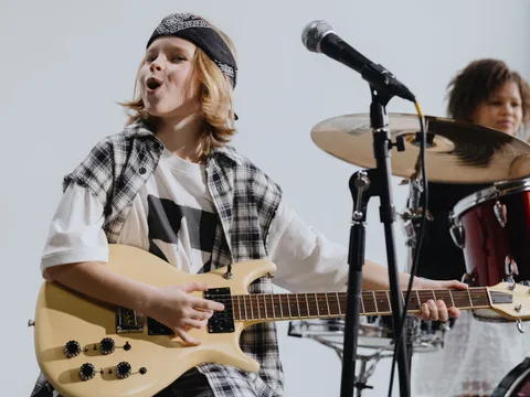 Young musicians passionately playing electric guitar and drums on stage.