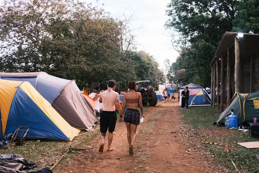 People walking past tents at a green campsite