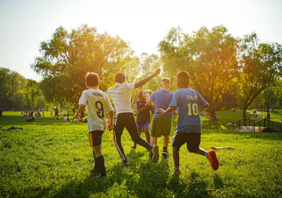Children playing football together on a sunny grass field